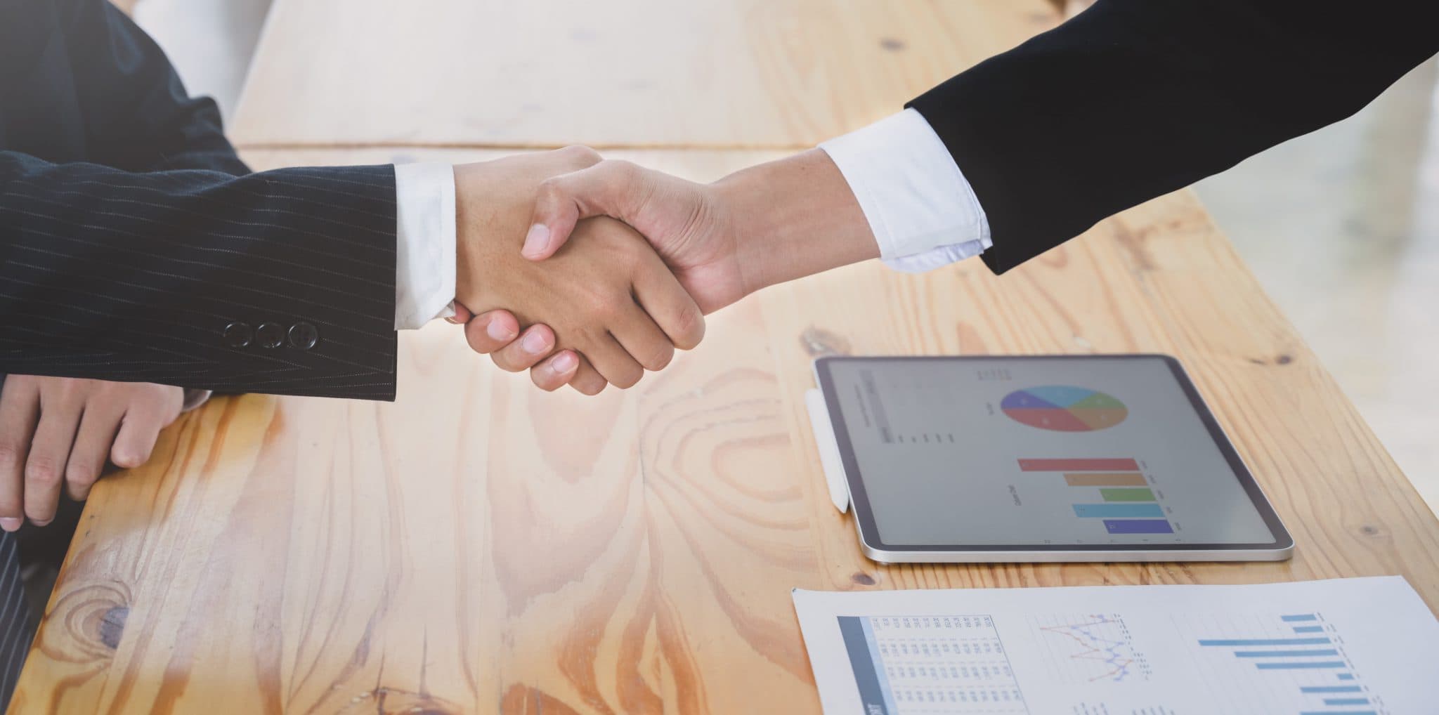 Business handshake over financial reports and analytics